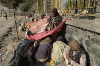 Heroin addicts, covered by a sheet, smoke opium at a park in Kabul on October 23, 2016