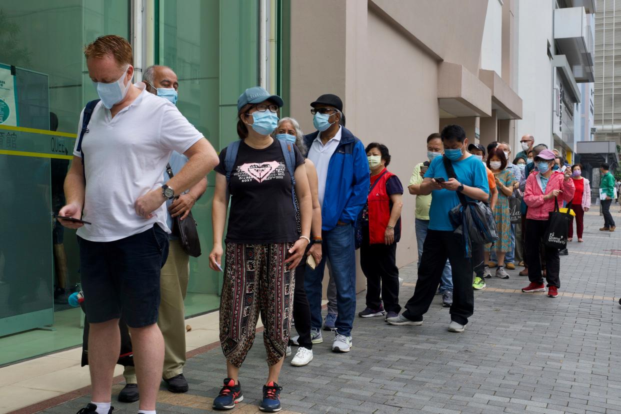 People queue up outside a vaccination center for BioNTech in Hong Kong on Tuesday, April 6, 2021. Hong Kong has resumed administering the vaccine developed by Pfizer and BioNTech in the city on Monday, following a 12-day suspension after packaging defects were detected in a batch of the shots.