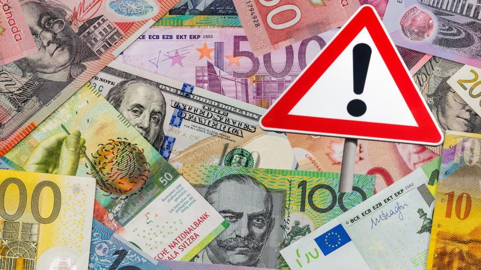 Compilation image of different currencies with a warning sign over the top tax