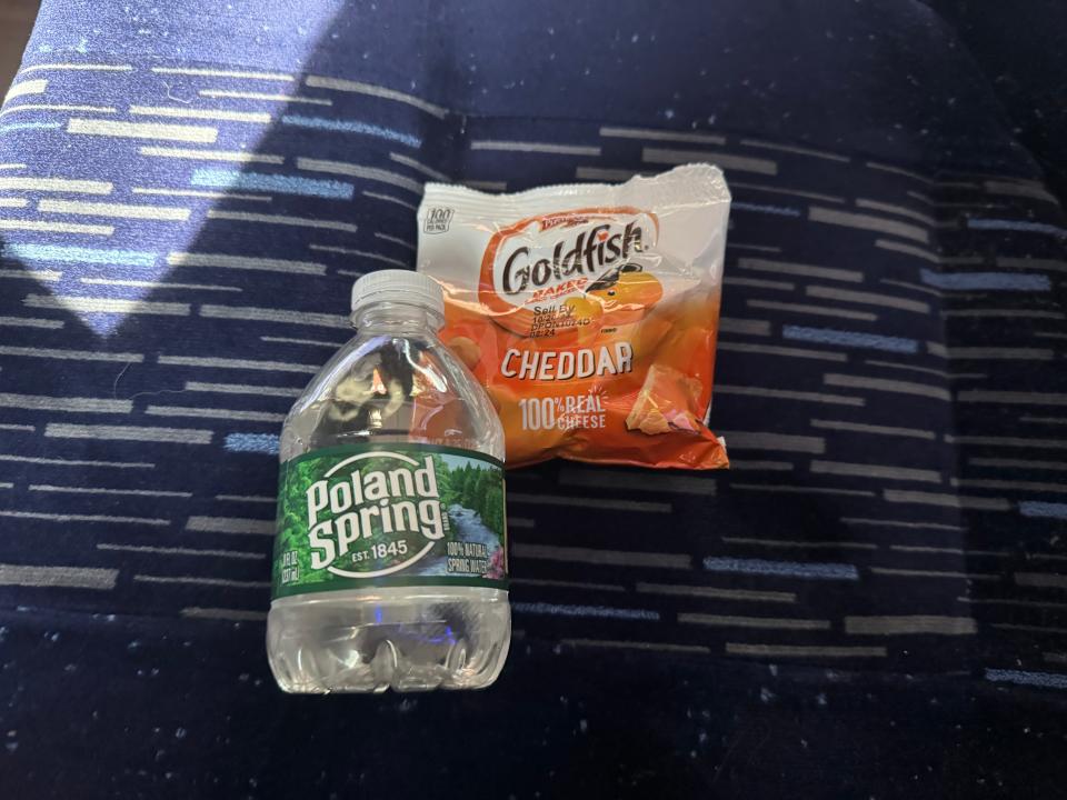 a small bottle of water and pack of goldfish on a bus seat