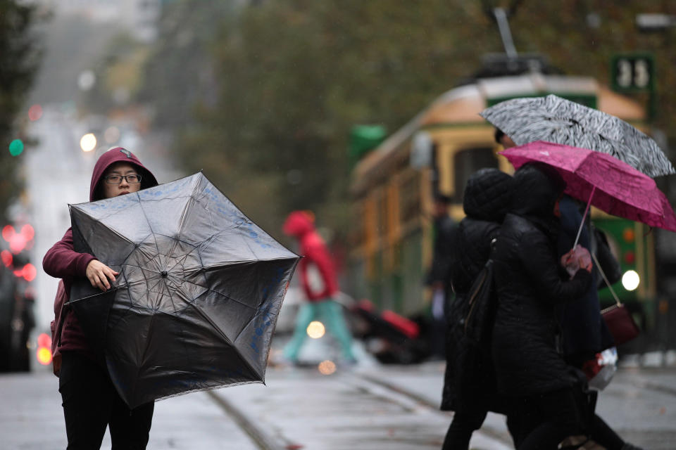 A woman struggles with her umbrella in the Melbourne CBD in May 2018. Victoria is set for two cold fronts and heavy winds this week.