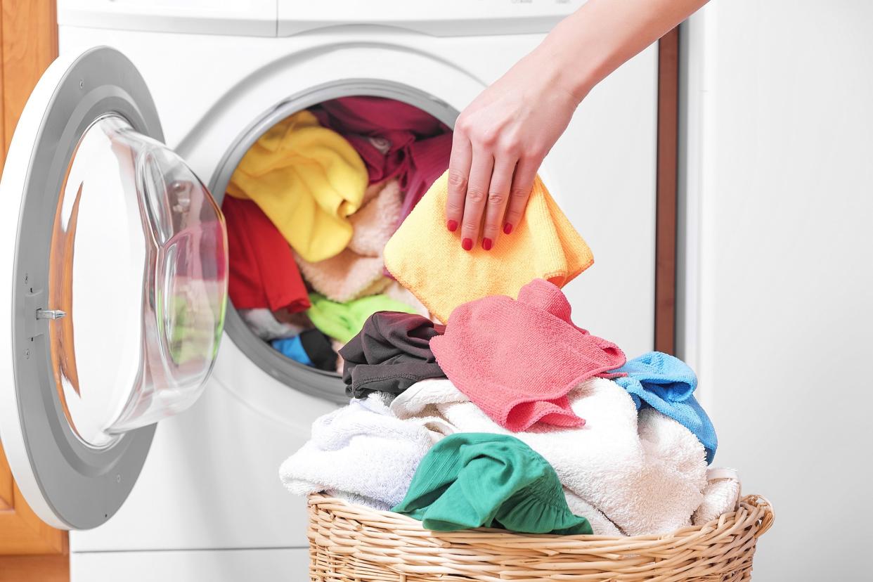 woman loading the washing machine colored clothing