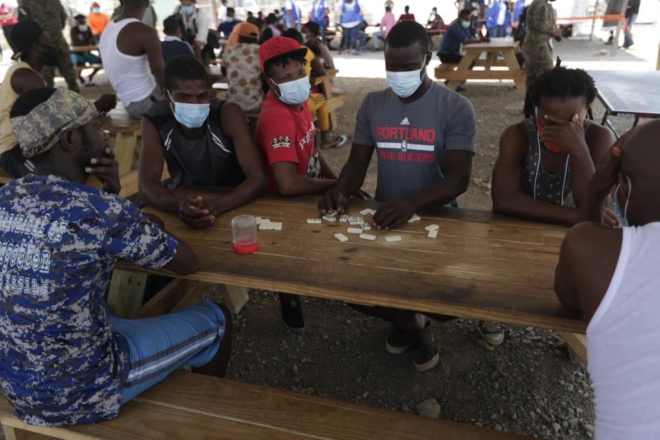 Haitian migrants play dominos at a migrant camp amid the new coronavirus pandemic in San Vicente, Darien province, Panama, Tuesday, Feb. 9, 2021. Panama is allowing hundreds of migrants stranded because of the pandemic, to move to the border with Costa Rica, after just reopening its land borders. (AP Photo/Arnulfo Franco)
