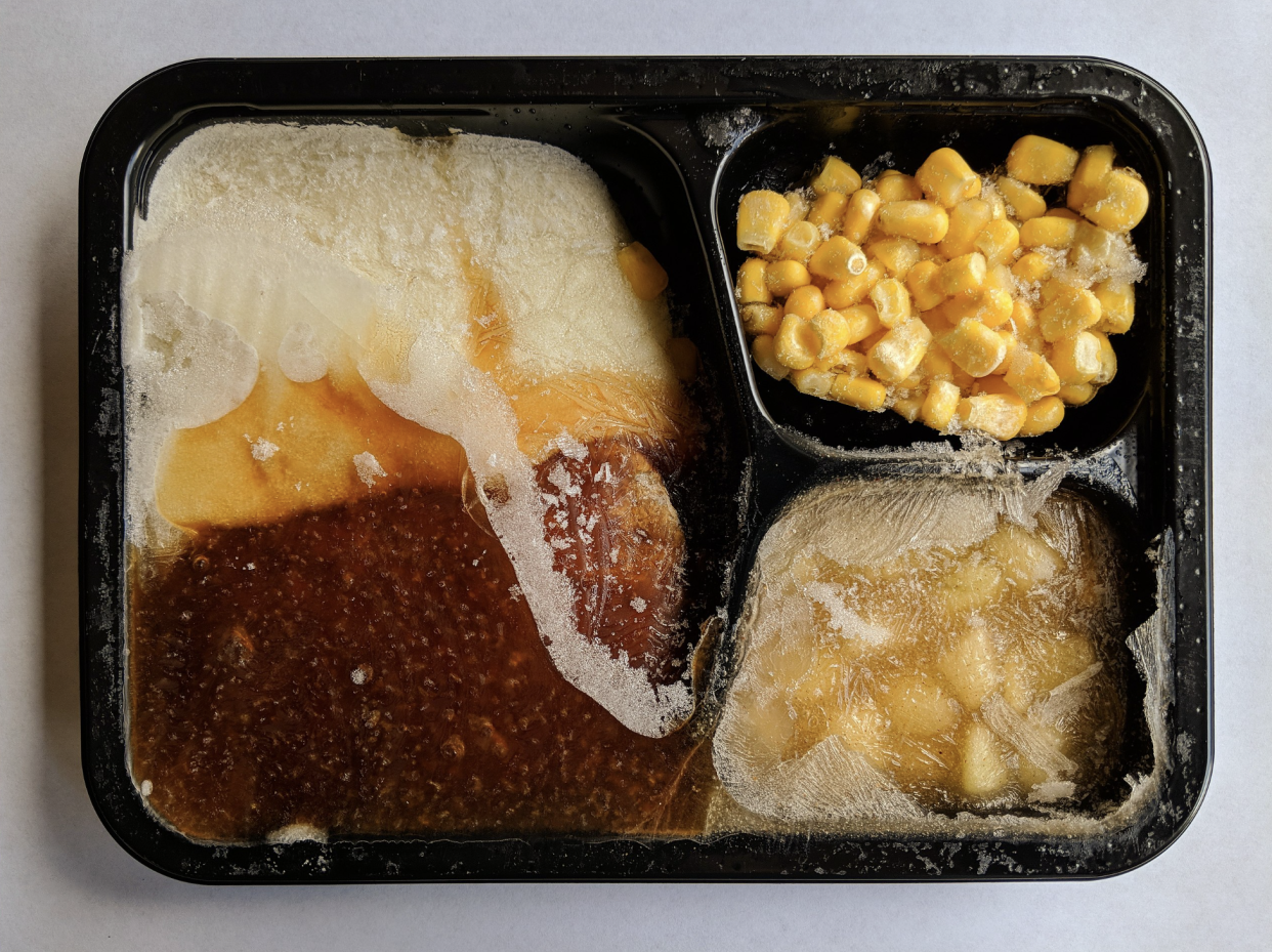 Top view of an opened, uncooked TV dinner.