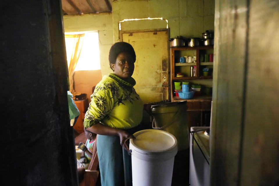 Jeff Carlos' wife, Christwish, is seen inside their home as she prepares to cook the days evening meal in Mabvuku on the outskirts of Harare on Wednesday, Aug, 3, 2022. Carlos, a father of three, says he gets about $100 dollars a month from his job as an overnight security guard for a church and the bar next door. Rising prices and a fast-depreciating currency have pushed many Zimbabweans to the brink, reminding people of when the southern African country faced world-record inflation of 5 billion % in 2008.(AP Photo/Tsvangirayi Mukwazhi)