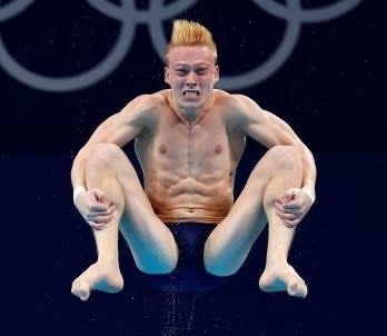 A diver in a tuck position mid-air