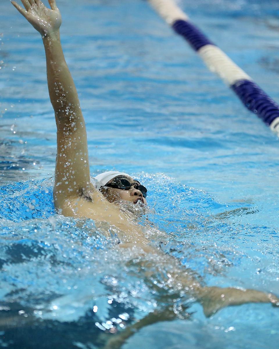 Quincy/North Quincy’s Isaac Ng reaches back during the 100 yard backstroke in their meet against Hingham at the Lincoln Hancock Pool in Quincy on Tuesday, Jan. 31, 2023. 