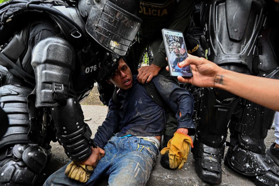 TOPSHOT - Colombian police officers arrest a demonstrator during a protest against the government in Cali, Colombia, on May 10, 2021. - Faced with angry street protests and international criticism over his security forces' response, Colombia President Ivan Duque is coming across as erratic and out of touch with a country in crisis, analysts say. Since April 28, hundreds of thousands of people have vented their frustrations against the government after poverty and violence soared during the pandemic. (Photo by Luis ROBAYO / AFP) (Photo by LUIS ROBAYO/AFP via Getty Images)