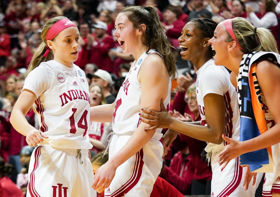 Indiana guard Sara Scalia (14) is congratulated by forward Mackenzie Holmes (54) and guards Chloe Moore-McNeil (22) and Sydney Parrish (33) during the Hoosiers' NCAA tournament first round game against Fairfield on Saturday at Simon Skjodt Assembly Hall in Bloomington, Ind.