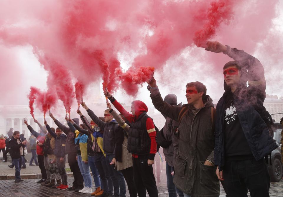 Protesters light flares during a rally as they gather in Independence Square in Kyiv, Ukraine, Sunday, Oct. 6, 2019. Thousands are rallying in the Ukrainian capital against the president's plan to hold a local election in the country's rebel-held east, a move seen by some as a concession to Russia. (AP Photo/Efrem Lukatsky)