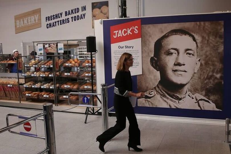 Woman walks past poster about Jack Cohen in a Tesco store