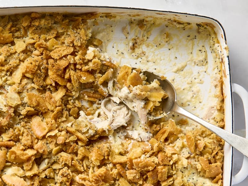 An overhead view of a white casserole dish of poppyseed chicken with a spoonful coming out.