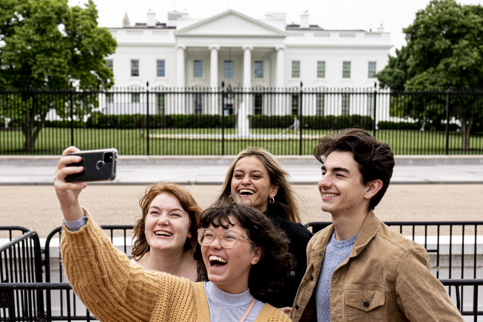From left, Eliana Lord, Carly Mihovich, Stephanie Justice, and Nick Hansen, visiting from Columbia, S.C., take a photo at Lafayette Park, across the street from the White House, after it reopens in a limited capacity in Washington, Monday, May 10, 2021. Fencing remains in place around the park which will allow the Secret Service to temporarily close the park as they deem necessary. (AP Photo/Andrew Harnik)