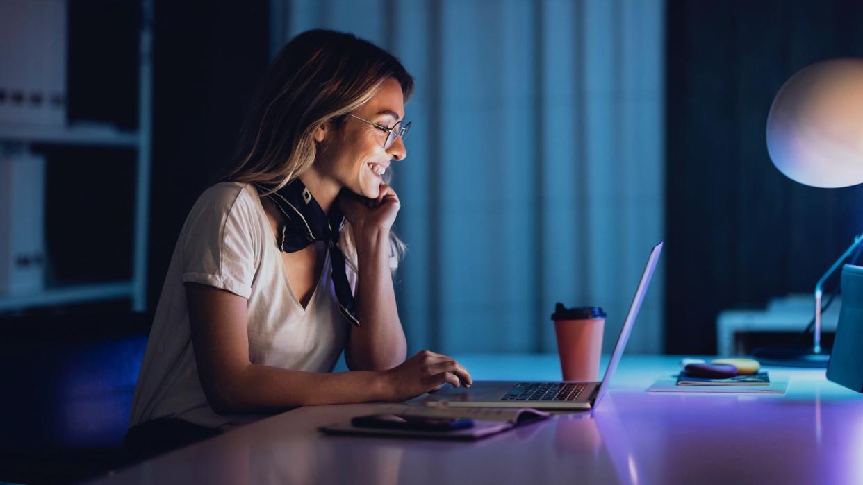  Young woman using a laptop inside at night 