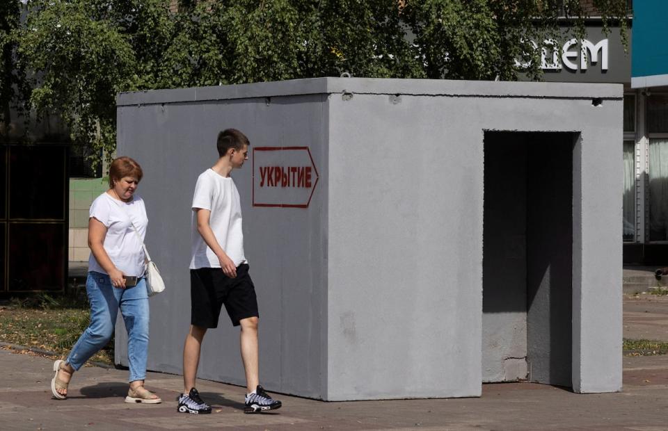 People walk past a reinforced concrete bomb shelter installed in a street in the course of Russia-Ukraine conflict, in Kursk, Russia August 28, 2024. The sign on the construction reads: "Shelter".