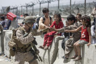 In this image provided by the U.S. Marine Corps, a Marine with Special Purpose Marine Air-Ground Task Force-Crisis Response-Central Command (SPMAGTF-CR-CC) plays with children waiting to process during an evacuation at Hamid Karzai International Airport in Kabul, Afghanistan, Friday, Aug. 20, 2021. (Sgt. Samuel Ruiz/U.S. Marine Corps via AP)