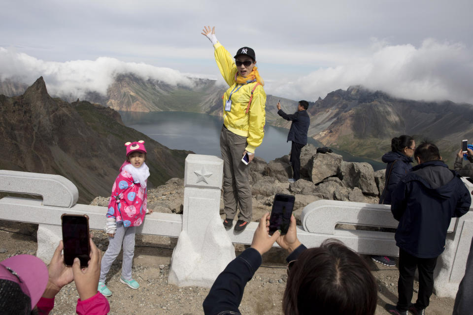 FILE - In this Aug. 18, 2018, file photo, Chinese tourists pose for photos overlooking the caldera of Mount Paektu in North Korea. There is no more sacred a place in North Korea than Mount Paektu. The still active volcano, site of one the most violent eruptions in history, is considered to be the spiritual epicenter of the North Korean revolution. (AP Photo/Ng Han Guan, File)