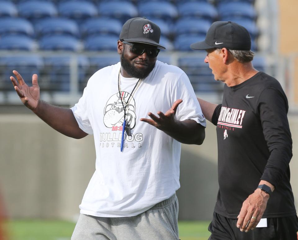 McKinley assistant coaches Shalamar Gilmer, left, and Joe Tresey confer prior to their scrimmage against St. Ignatius at Tom Benson Hall of Fame Stadium on Friday, August 13, 2021.