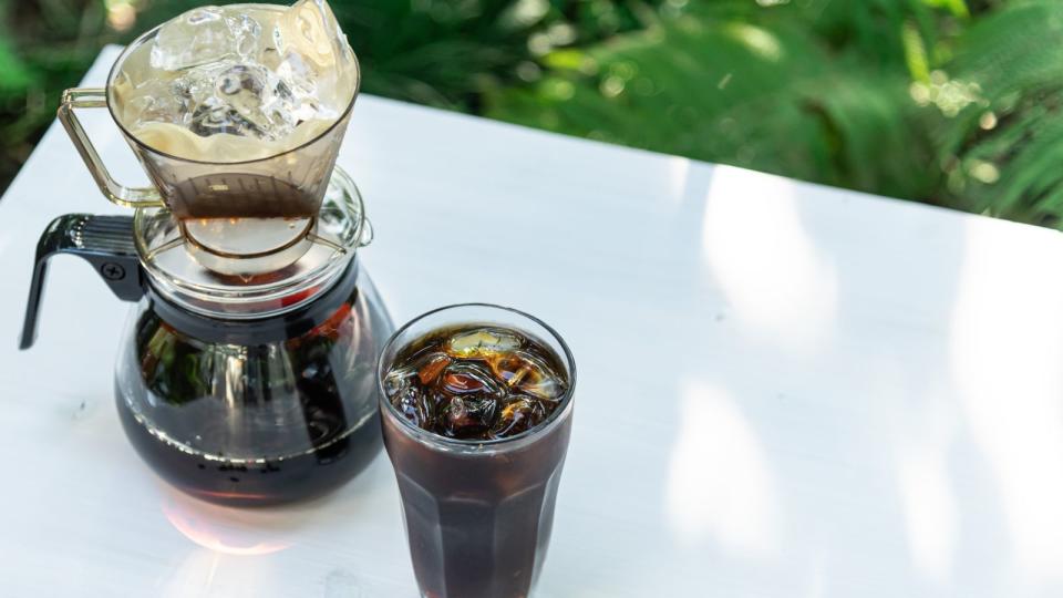 A drip coffee maker brewing iced coffee on a table