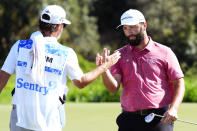 Jon Rahm, of Spain, celebrates his birdie putt with his caddie on the 18th green during the final round of the Tournament of Champions golf event, Sunday, Jan. 8, 2023, at Kapalua Plantation Course in Kapalua, Hawaii. (AP Photo/Matt York)