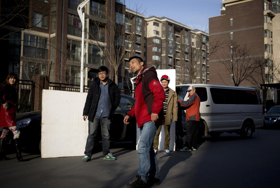 In this Dec. 4, 2013 photo, Chinese director Sun Zhendong, foreground, checks the sunlight as his crew prepares to film the “Mr. Ball” microfilm near a residential buildings in Changping, on the outskirts of Beijing. Microfilms, uploaded to Chinese YouTube-style and video-streaming sites, offer themes and subjects you won’t come across in China’s strictly censored cinemas. And thanks to video-capturing smartphones and basic editing software available on laptops, anyone can be a director these days. (AP Photo/Andy Wong)