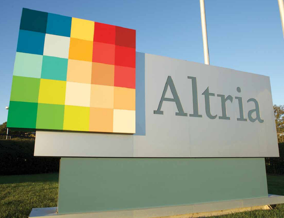 Altria logo sign in front of a grass field with trees on a clear day.