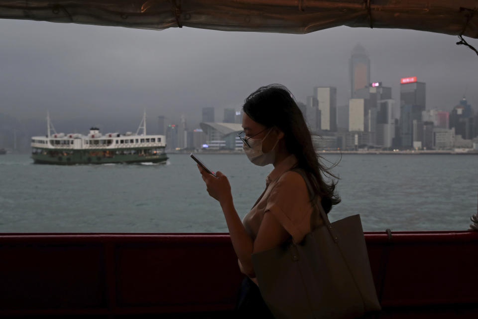 In this Thursday, May 28, 2020, photo, a woman uses a smartphone on a ferry in Hong Kong. Hong Kong has been living on borrowed time ever since the British made it a colony nearly 180 years ago, and all the more so after Beijing took control in 1997, granting it autonomous status. A national security law approved by China's legislature Thursday is a reminder that the city's special status is in the hands of Communist Party leaders who have spent decades building their own trade and financial centers to take Hong Kong's place. (AP Photo/Kin Cheung)