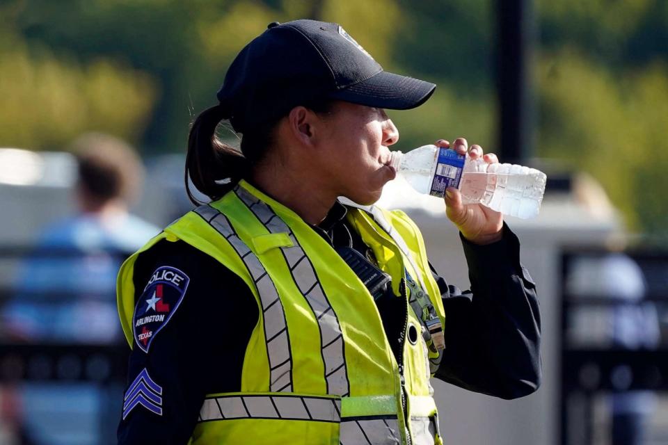 PHOTO: A police officer directing traffic takes a break to drink water after a sporting event in Arlington, Texas, Aug. 19, 2023. (Lm Otero/AP)
