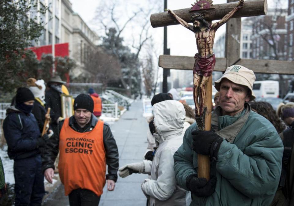 A pro-choice activist walks past pro-life activists during a protest outside Planned Parenthood January 24, 2013 in Washington DC.