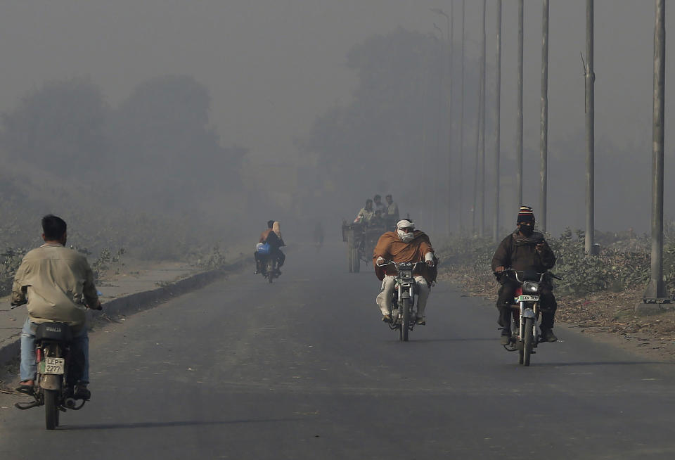 Motorcyclists drive along a road as smog envelops the area of Lahore, Pakistan, Monday, Nov. 22, 2021. People of Lahore and adjacent area are suffering from respiratory problems because of poor air quality related to thick smog hanging over the region. (AP Photo/K.M. Chaudary)