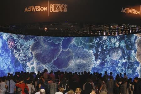 Visitors look at a presentation at the ActiVision Blizzard exhibition stand during the Gamescom 2013 fair in Cologne August 21, 2013. REUTERS/Ina Fassbender