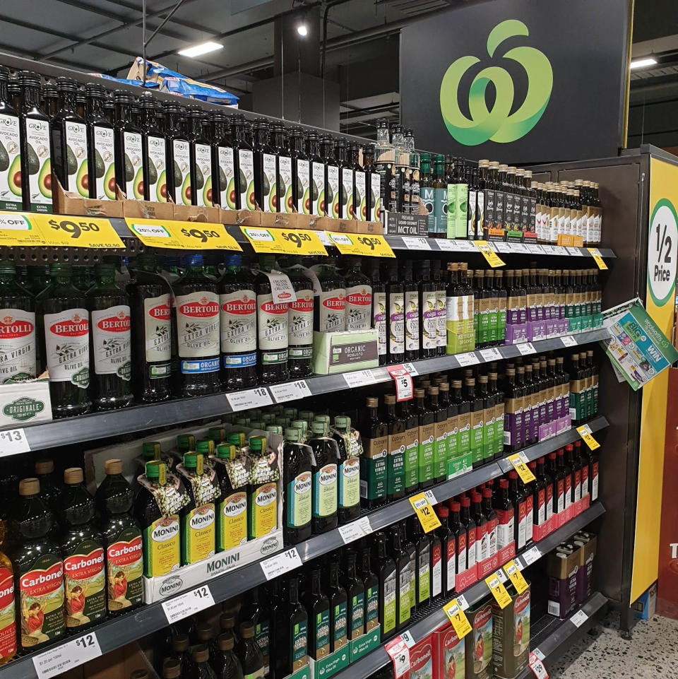 An aisle in Woolworths showing shelves filled with bottled of olive oil.