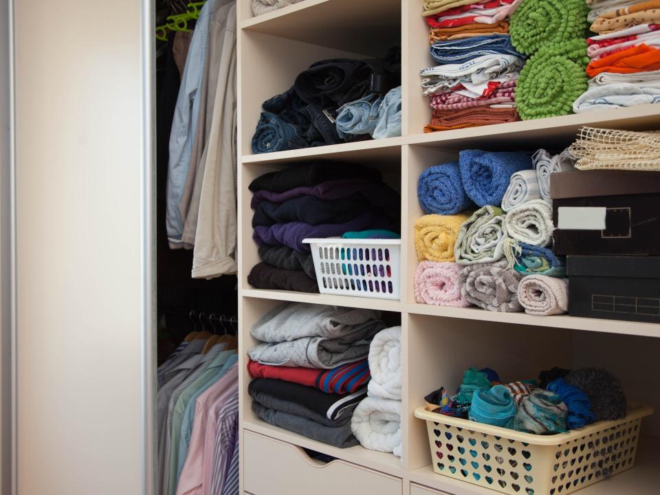 Closet with shelves of multicolored towels and clothes