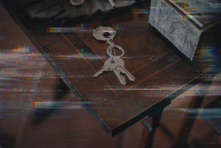 A set of keys on a wooden table surface, with visual interference disrupting the image clarity