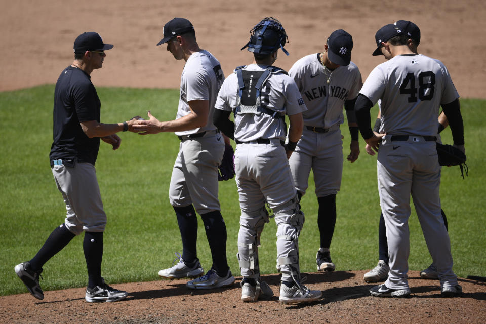 New York Yankees manager Aaron Boone, left, pulls starting pitcher Carlos Rodon, second from left, during the fifth inning of a baseball game against the Baltimore Orioles, Thursday, May 2, 2024, in Baltimore. (AP Photo/Nick Wass)