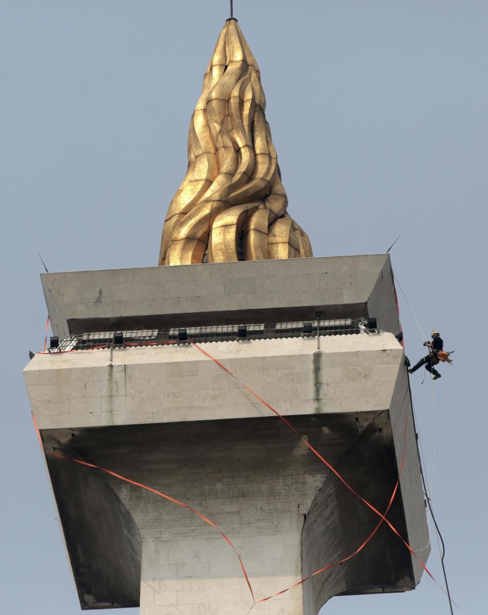 In this Thursday, May 8, 2014 photo, a worker rappels down from the top of the National Monument to prepare for its cleaning in Jakarta, Indonesia. The 132-meter (433-feet) tall monument, a popular landmark in the capital, is being cleaned for the first time in more than two decades. German-based Kaercher company, which specializes in the cleaning of cultural monuments, is doing the work. It also did the monument’s last cleaning in 1992. (AP Photo/Dita Alangkara)