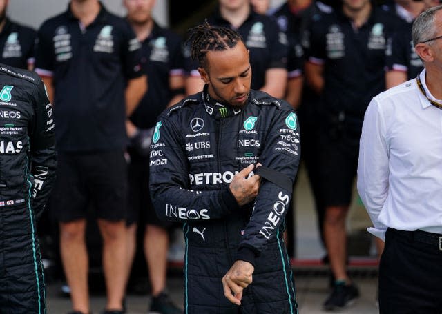 Lewis Hamilton adjusts the black armband on his Mercedes race suit