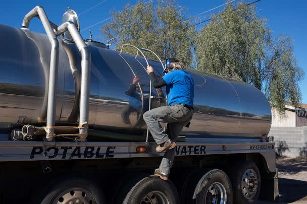 PHOTO: John Hornewer climbs down the ladder of his tanker as he fills it up to haul water to Rio Verde Foothills, Jan. 7, 2023, in Apache Junction, Ariz. (The Washington Post via Getty Images)