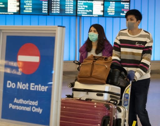 Passengers wear masks to protect against the spread of the novel coronavirus as they arrive at Los Angeles International Airport