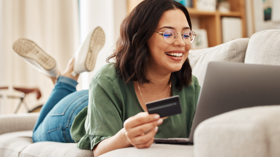 Woman on couch with laptop online shopping with credit card - Jacob Wackerhausen/iStockphoto