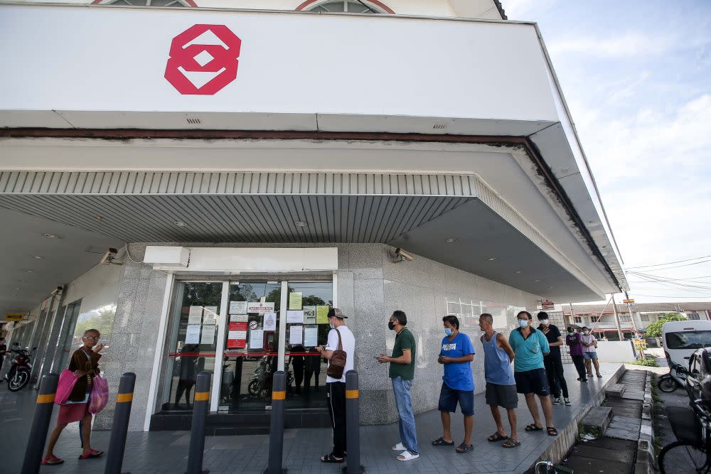 Members of the public observe social distancing guidelines as they queue outside a Public Bank branch in Ipoh March 26, 2020. — Picture by Farhan Najib