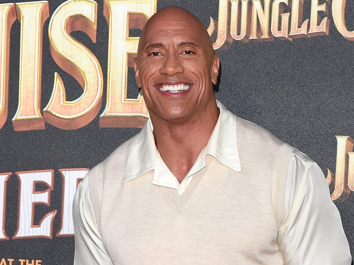 Dwayne Johnson dressed in all white with a black belt and shoes