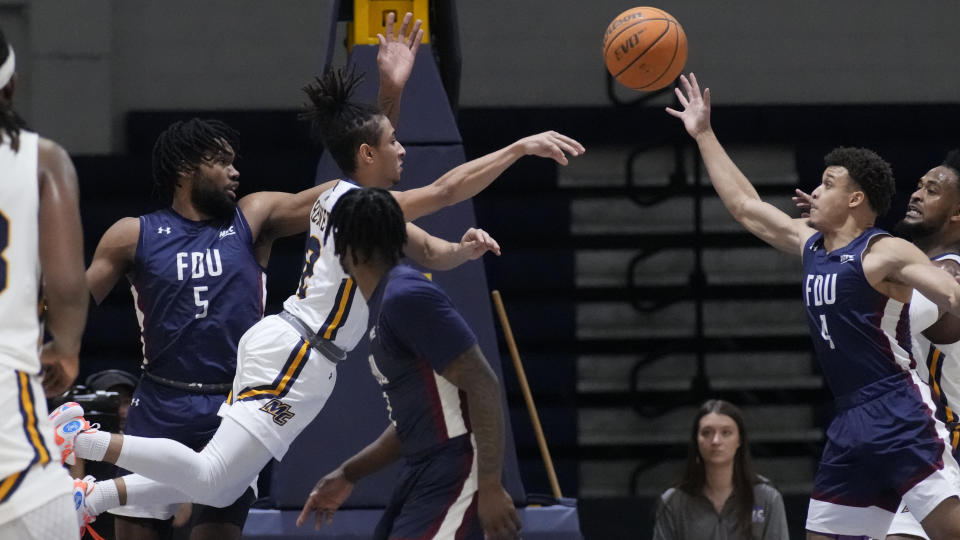 Merrimack guard Javon Bennett, center, passes the ball while pressured by Fairleigh Dickinson's Ansley Almonor (5) and Grant Singleton (4) during the first half of Northeast Conference men's NCAA college basketball championship game, Tuesday, March 7, 2023, in North Andover, Mass. (AP Photo/Charles Krupa)