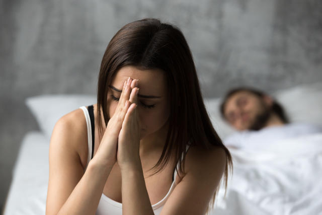 Upset frustrated sad millennial woman feeling troubled with unwanted pregnancy, jealousy, abortion or bad relationship problems thinking of breaking up or divorce while boyfriend sleeping in bed