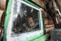 RNPS - PICTURES OF THE YEAR 2013 - Former bargeman Viktor, 57, who refused to give his family name, looks out of a window of his wooden hut located in a forest some 55 km (34 miles) south of Russia's Siberian city of Krasnoyarsk, October 17, 2013. A decade ago, Viktor decided to lead the life of a hermit, and settled in this secluded forest area hidden from civilisation. He reads the Bible, and survives mainly on fish, berries, mushrooms and other food he can find. REUTERS/Ilya Naymushin (RUSSIA - Tags: ENVIRONMENT SOCIETY TPX)