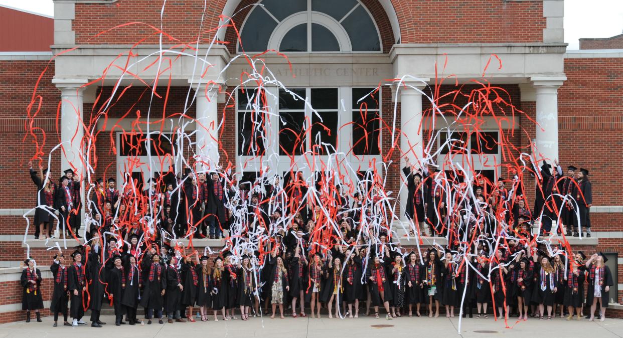 Members of the Monmouth College Class of 2022 celebrate their class photo by throwing streamers on Sunday morning in front of the College's Huff Athletic Center.