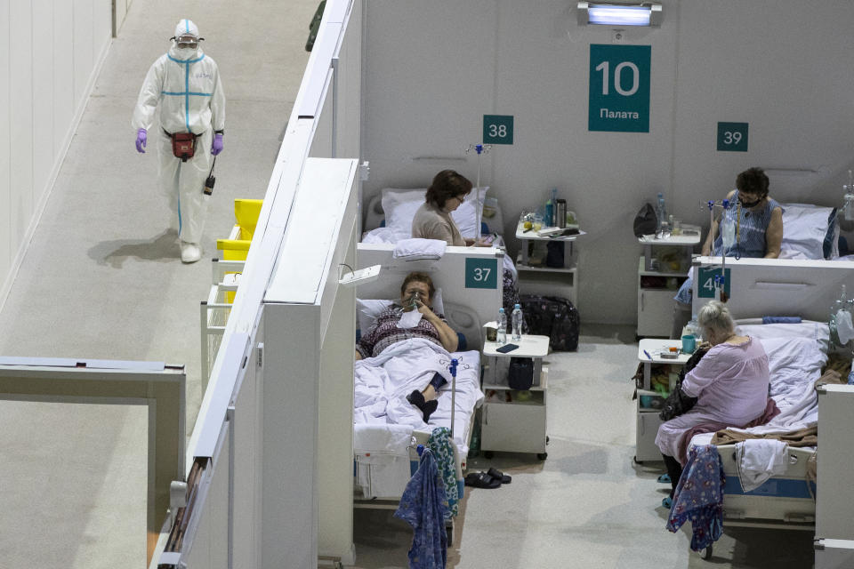 A medical worker walks next to patients in the treatment hall of a temporary hospital for coronavirus patients in the Krylatskoye Ice Palace in Moscow, Russia, Wednesday, Nov. 18, 2020. Russia’s health care system has been under severe strain in recent weeks, as a resurgence of the coronavirus pandemic has swept the country. (AP Photo/Pavel Golovkin)