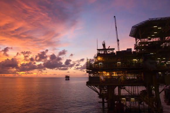 An offshore oil rig at sunset.