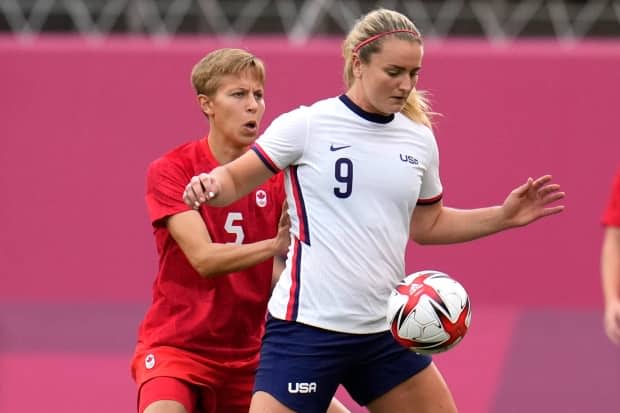 Canada's Quinn, left, and Lindsey Horan of the United States battle for the ball during their semifinal soccer match at Tokyo 2020 at Kashima Stadium on Monday. (Fernando Vergara/The Associated Press - image credit)