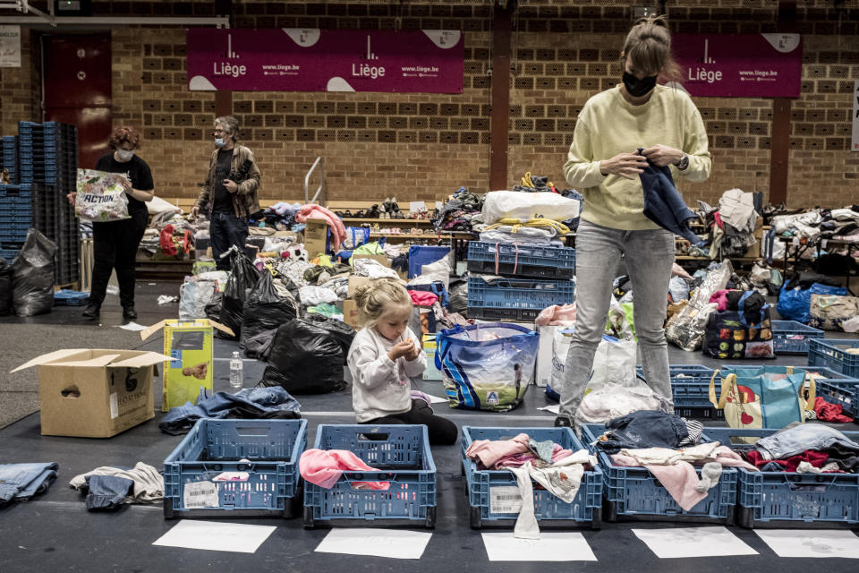 A woman sorts through clothing in a shelter for residents after flooding in Angleur, Province of Liege, Belgium, Friday July 16, 2021. Severe flooding in Germany and Belgium has turned streams and streets into raging torrents that have swept away cars and caused houses to collapse. (AP Photo/Valentin Bianchi)